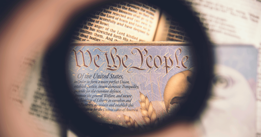 Looking through the lens of a magnifying glass at the Declaration of Independence, focused on the words "We the People"